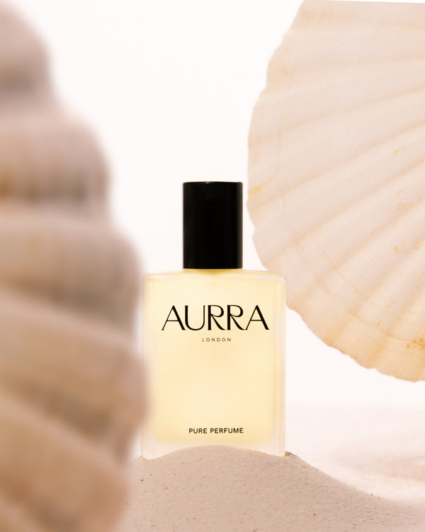 AURRA London pure perfume bottle with seashells in the background