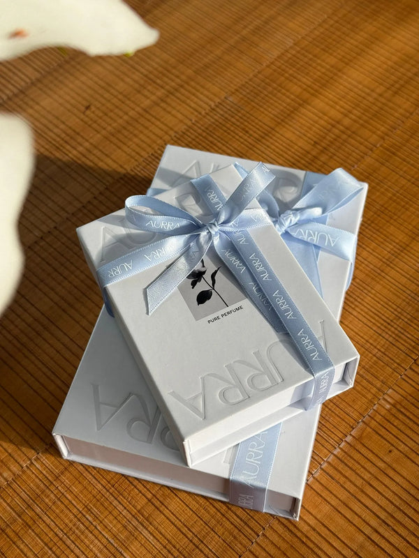 Two white boxes with blue ribbons on a wooden surface